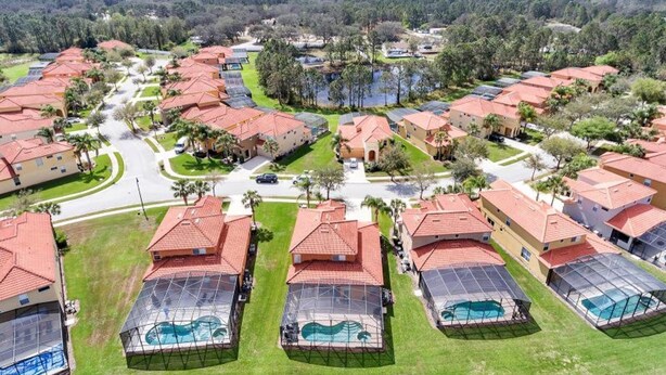 A residential area with multiple houses, each with a red roof and a swimming pool covered by a transparent roof. - Watersong - Luxurious 5bd/4.5ba Pool Home #5wr510 (Davenport)