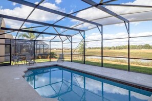 Una piscina techada con vistas a un paisaje con césped y un cielo despejado.