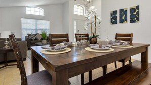 A dining room with a large wooden table set for four, surrounded by chairs. There is a chandelier above the table, and the room has a modern, clean design with a large window and a door leading to another room. - Davenport - New Listing 4bd/3ba Home - #4av410 (Davenport)
