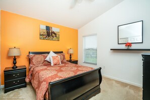 Quarto com cama, mesas de cabeceira, luminária, espelho e janela com persianas.