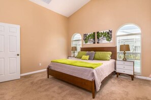 Quarto com cama, mesas de cabeceira e duas luminárias fixadas na parede.