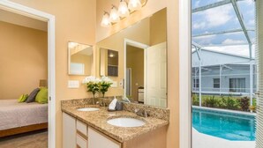 Une salle de bain avec deux lavabos, un grand miroir et une vue sur une piscine.