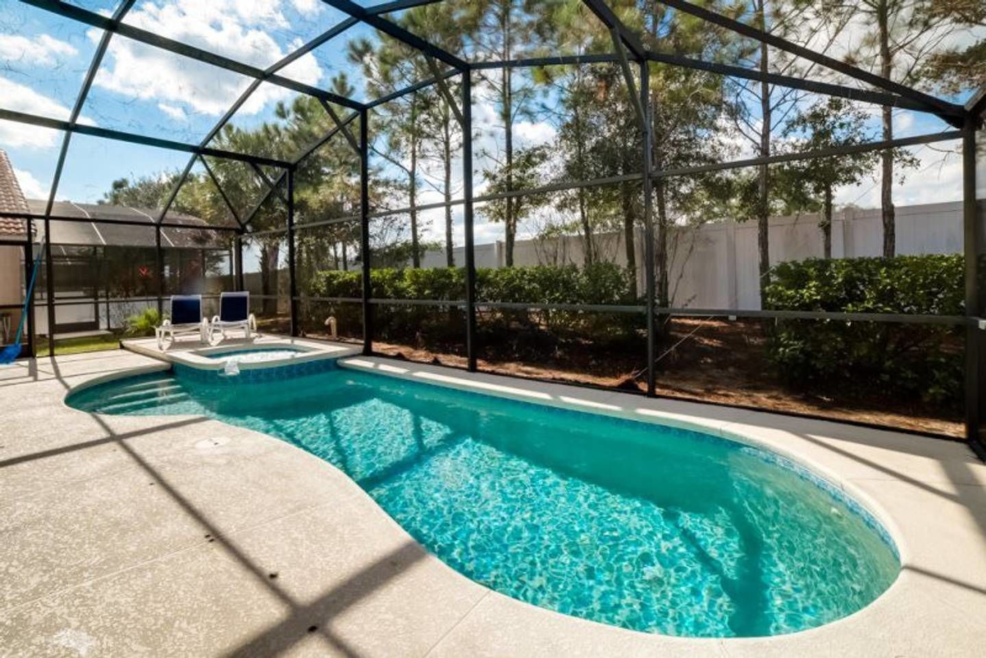 A swimming pool with a curved design, surrounded by a covered area with a metal frame and glass panels.