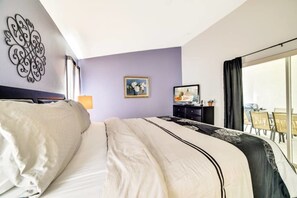 Une chambre d’hôtel avec un grand lit, une télévision, un bureau avec un ordinateur et une fenêtre donnant sur l’extérieur.