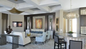 A modern living room with a white sofa, a coffee table, and a dining area with a bar. - Solterra Resort - Brand NEW 5bed Pool Home #5st417 (Davenport)