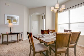 A dining area with a wooden table and chairs, a chandelier, and a mirror on the wall. - Hampton Lakes - Lovely 4bd/3ba Pool Home 4hl904 (Davenport)