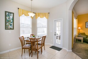 Cozy dining area with a round table and four chairs, featuring a door to an outdoor space with a chair and table.