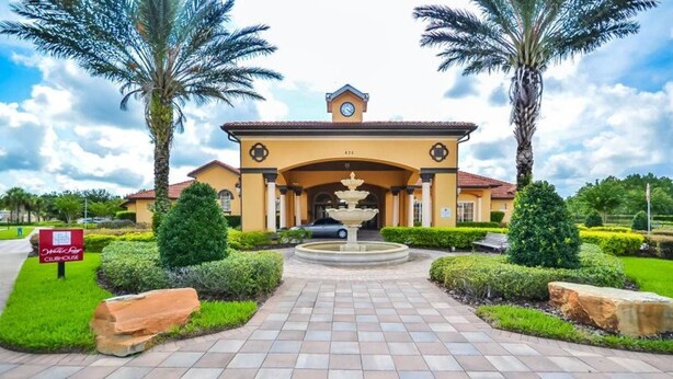 A building with a central fountain, palm trees, and a sign for a clubhouse. - Watersong - 6bd/5.5ba Pool Home #6wr120 (Davenport)
