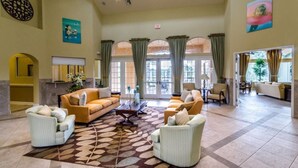 A spacious lobby with a large sofa set, a coffee table, and a patterned rug. There are multiple seating areas and a large window with curtains. - Watersong - 6bd/5.5ba Pool Home #6wr120 (Davenport)