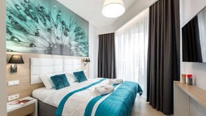 Une chambre d’hôtel moderne dotée d’un grand lit, d’une table de chevet, d’un téléviseur fixé au mur et d’une grande fenêtre avec des rideaux.