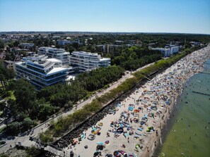 A coastal cityscape with modern buildings, a busy beach, and a clear sky. - DUNE C - FAF (Mielno)