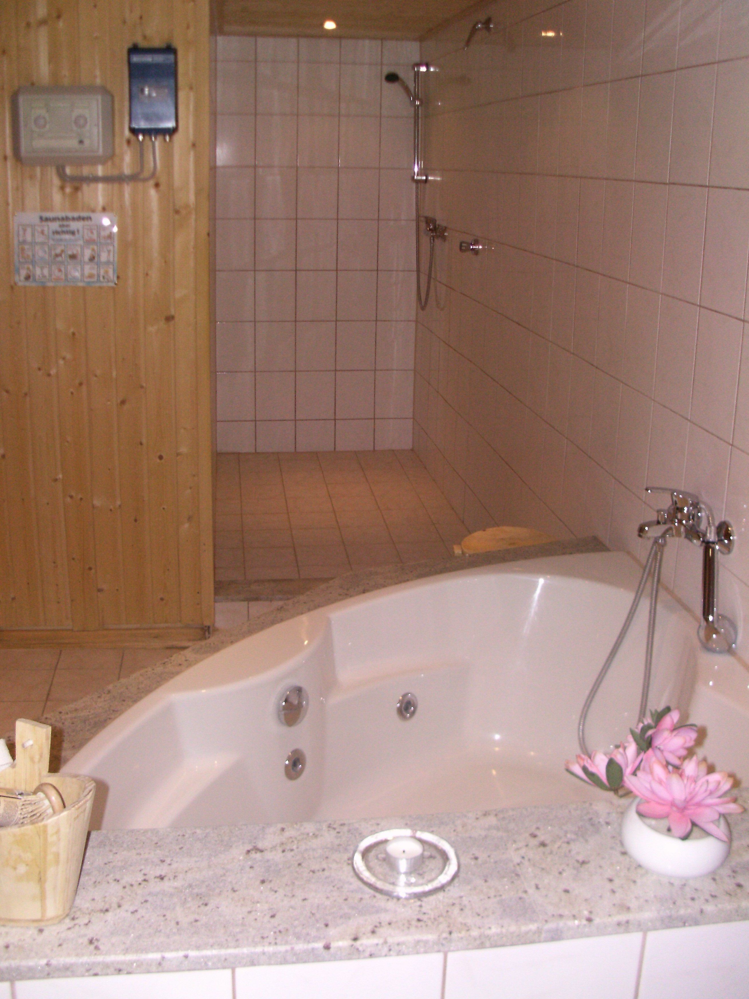 Un bagno con vasca, doccia e parete rivestita in legno.