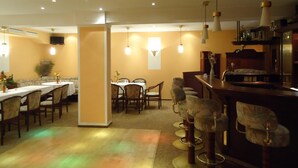 A restaurant with a bar area, multiple tables, and chairs. - Hotel-Restaurant Marcus (Malchin)