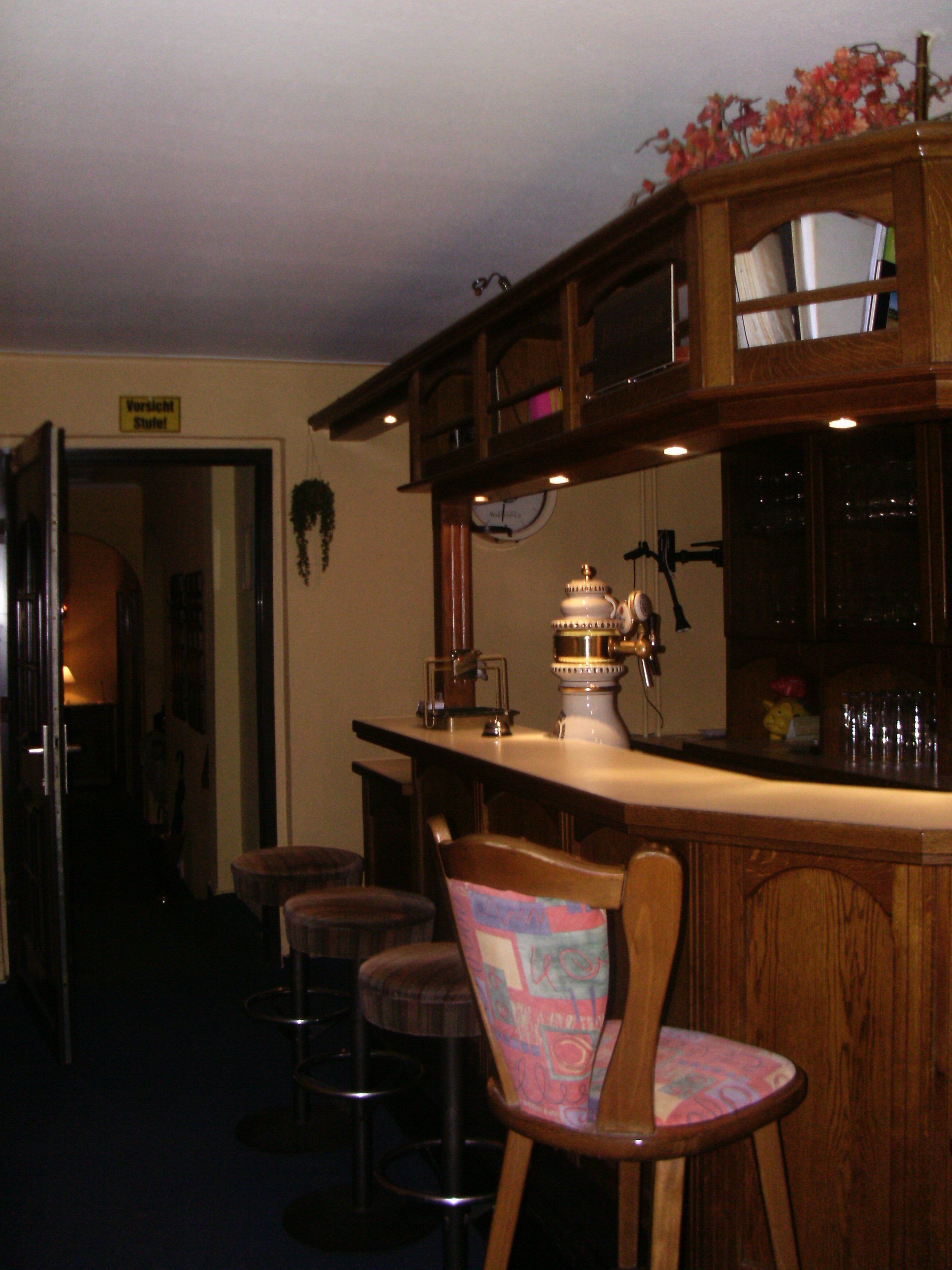 A bar area with wooden furniture, a clock, and a sign that reads "Vorsicht Stuhle."