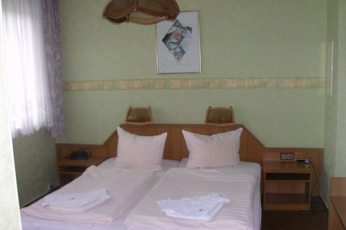 A double bed with two pillows, a bedside table, and a nightstand with a lamp.