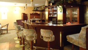 A bar area with a wooden counter, bar stools, and hanging pendant lights. - Hotel-Restaurant Marcus (Malchin)