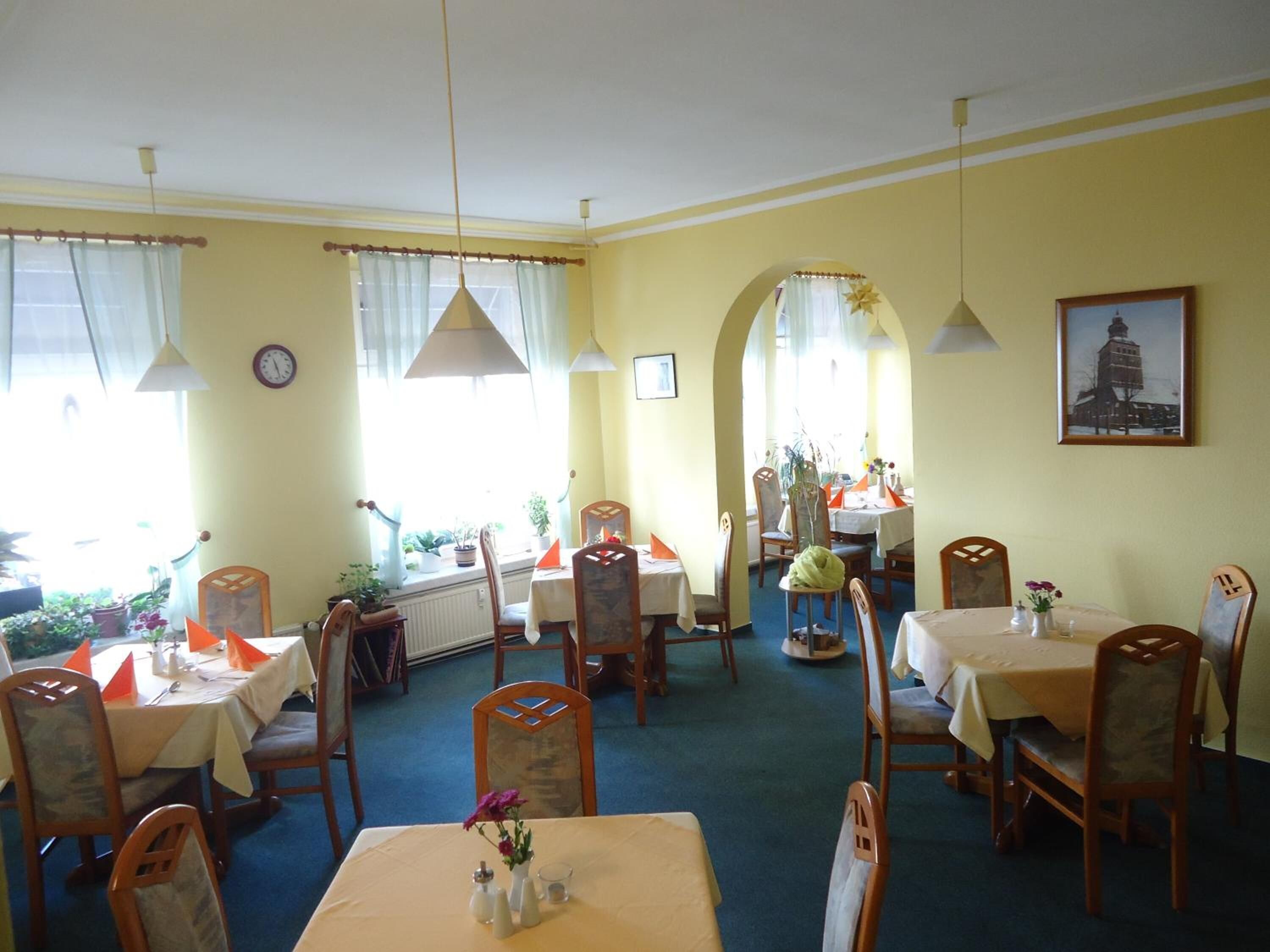 A dining area with multiple tables and chairs, a clock on the wall, and a framed picture.