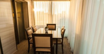 Ein Speisesaal eines Hotels mit einem runden Tisch, sechs Stühlen und einer Zimmerpflanze.