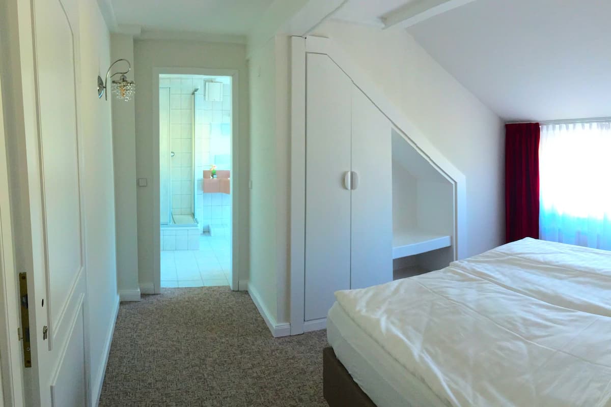 A bedroom with a bed, a wardrobe, and a window with curtains.