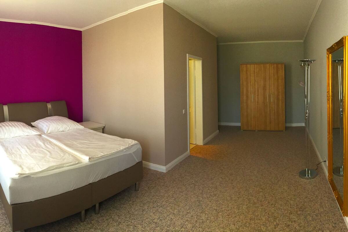 A bedroom with a bed, a nightstand, a wardrobe, and a mirror.