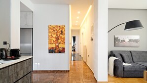 A modern kitchen with a refrigerator, coffee maker, and a painting on the wall. - Acropolis Plus Penthouse (Athens)