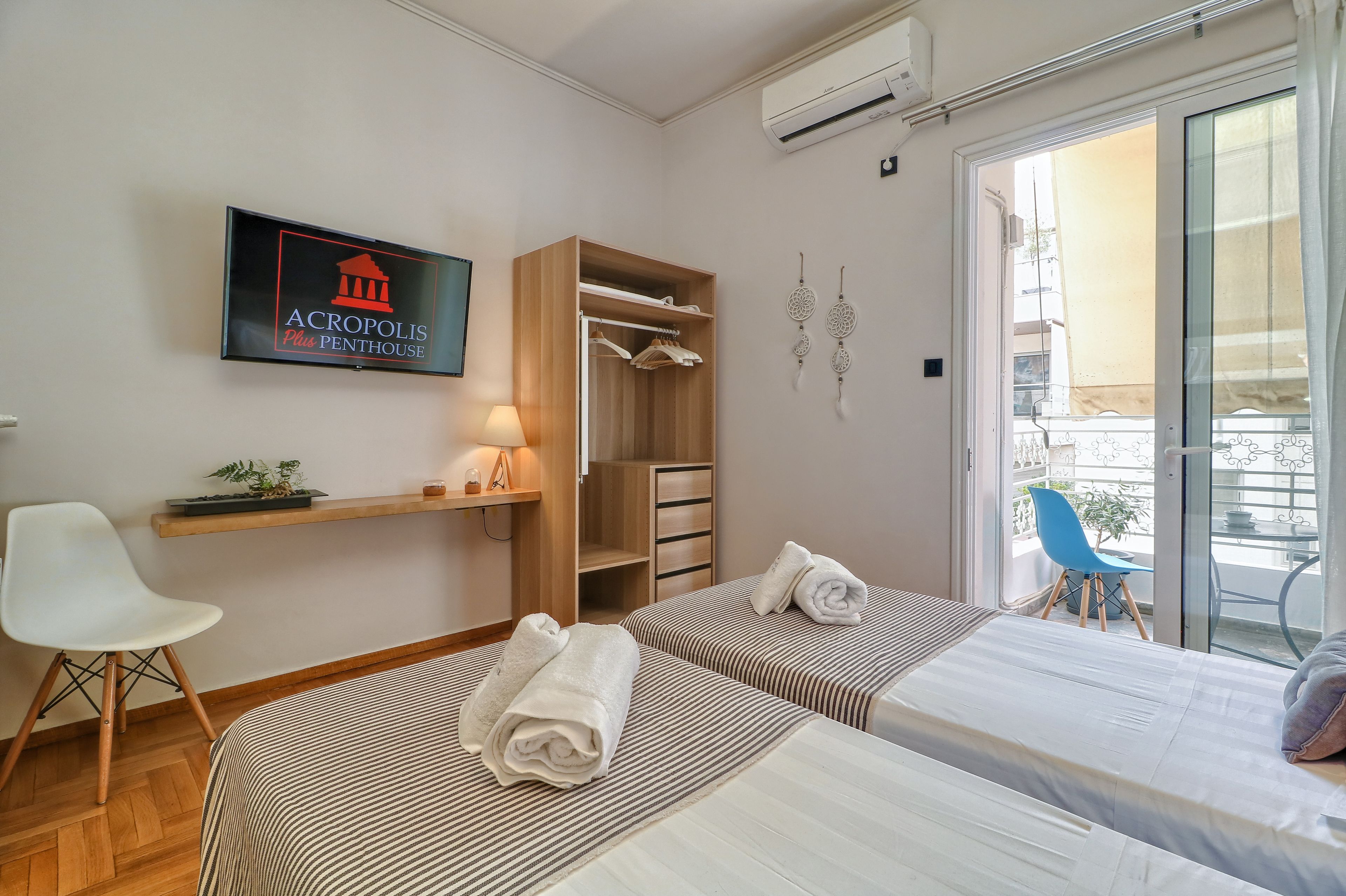 Une chambre d’hôtel avec deux lits, une armoire, un bureau, une chaise et un balcon équipé d’une chaise.