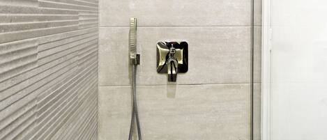 A modern bathroom with a shower, a towel rack, and a door.