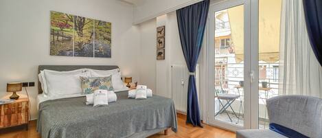Une chambre d’hôtel avec un lit, une chaise, un tableau et une vue sur le balcon extérieur.