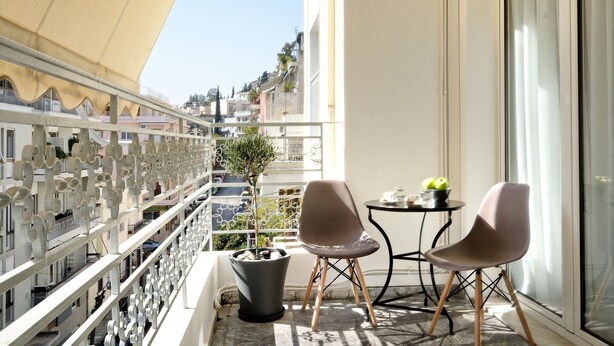 A balcony with a potted plant, two chairs, a small table, and a view of the cityscape. - Acropolis Plus Penthouse (Athens)