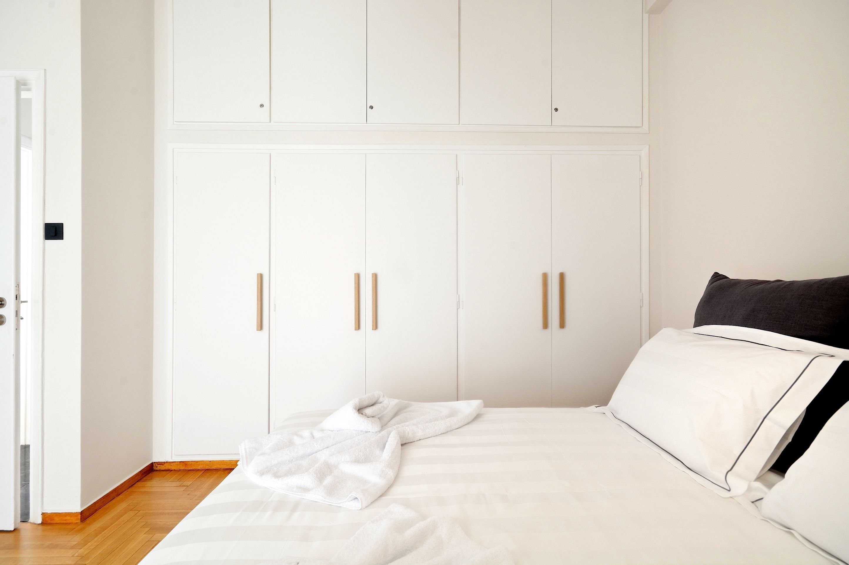 A bedroom with a bed, white wardrobe, and a door.