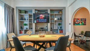 A dining area with a wooden table, black chairs, and a decorative bowl centerpiece. Shelves with books and decorative items are in the background. - Acropolis Plus Penthouse (Athens)