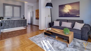 A modern living room with a grey sofa, wooden coffee table, and a painting of a moonlit scene. - Acropolis Plus Penthouse (Athens)