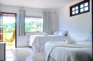 Habitación de hotel con dos camas, un balcón con hamaca y vistas al verde.