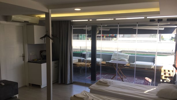 Habitación de hotel con kitchenette, cama, sofá y balcón con vista a la ciudad.