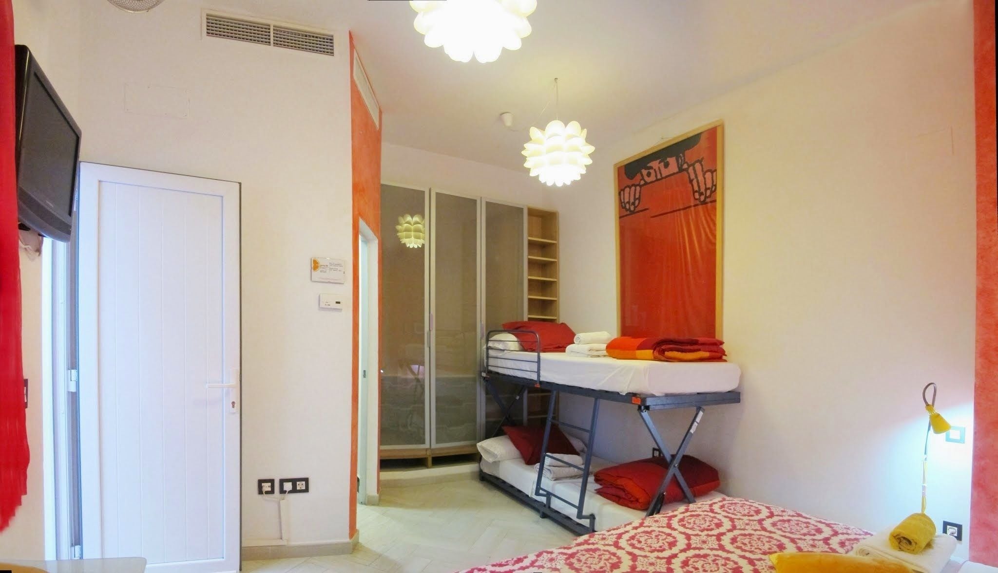 A dorm-style room with bunk beds, a wardrobe, and a small desk.