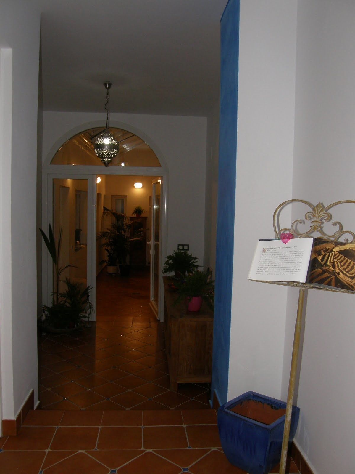 A hallway with a tiled floor, a hanging light fixture, and a blue curtain.