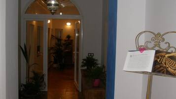 A hallway with a tiled floor, a hanging light fixture, and a blue curtain.