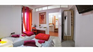 A hotel room with two beds, a desk, and a bathroom visible through an open door.
