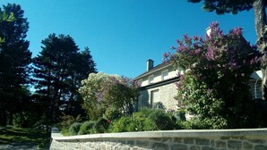 A stone house with a garden, surrounded by trees and flowering plants. - Chez Louis - Chambres d'Hôtes (La Canourgue)
