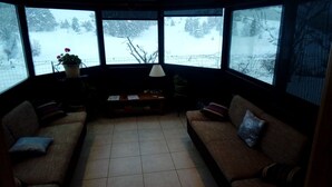 A cozy corner room with a large window offering a snowy outdoor view. - Chez Louis - Chambres d'Hôtes (La Canourgue)