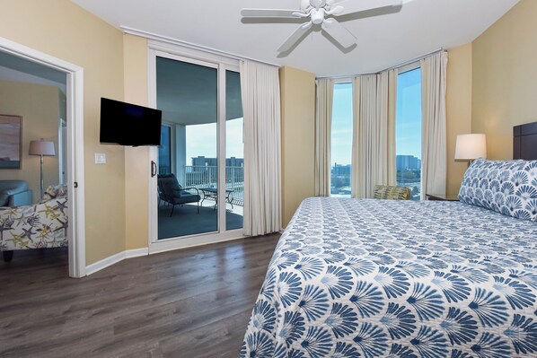 A hotel room with a bed, a television, a ceiling fan, a balcony with a view, and a chair. - Spacious open-concept resort condo w/private balcony in Destin! (Destin)