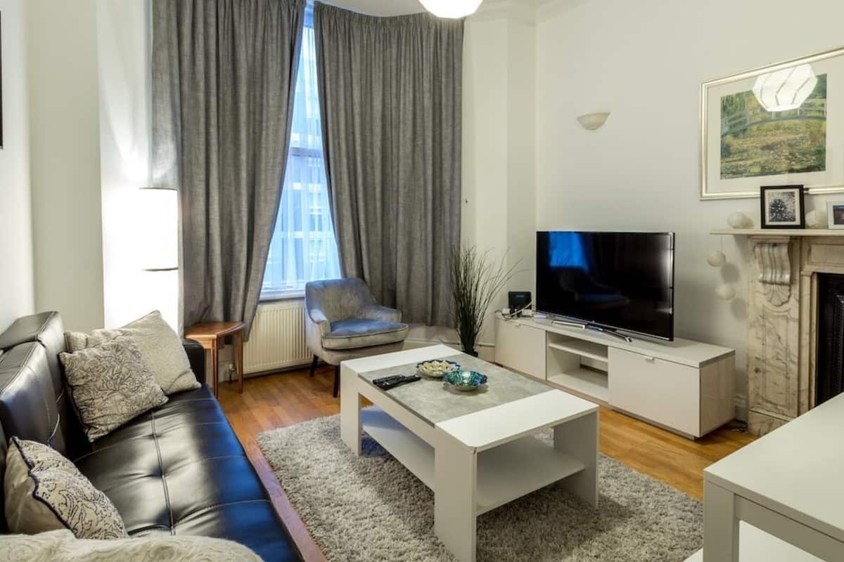 Ein modernes Wohnzimmer mit Sofa, Couchtisch, Fernseher und Kamin.