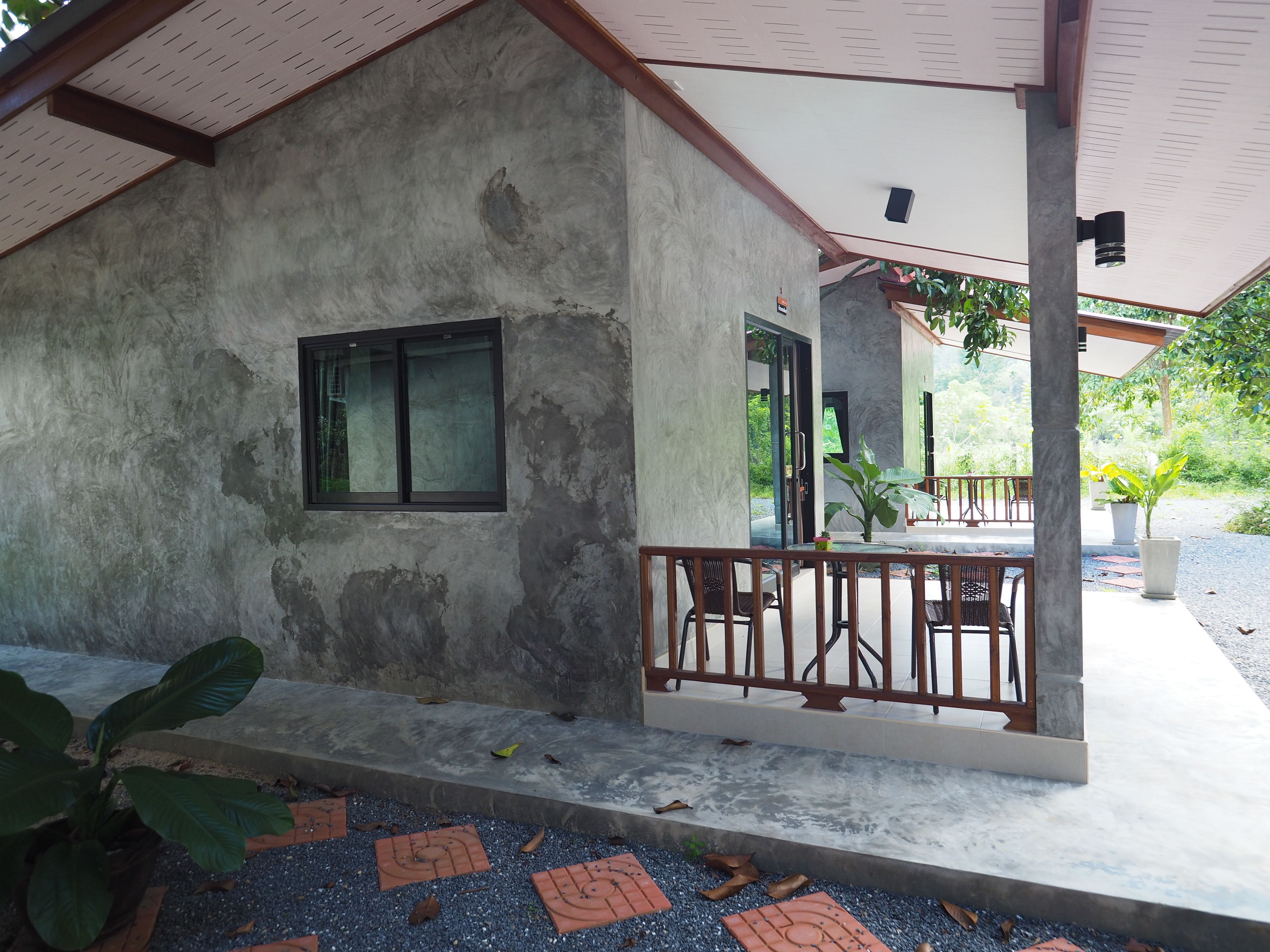 A covered outdoor area with a concrete wall, a window, and a table with chairs.