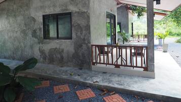 A covered outdoor area with a concrete wall, a window, and a table with chairs.