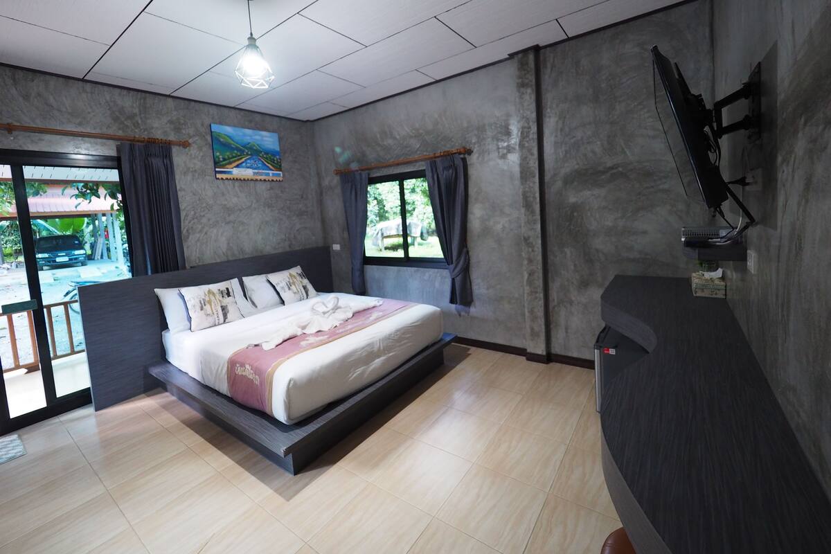 A modern hotel room with a bed, a desk, and a view of the outside.