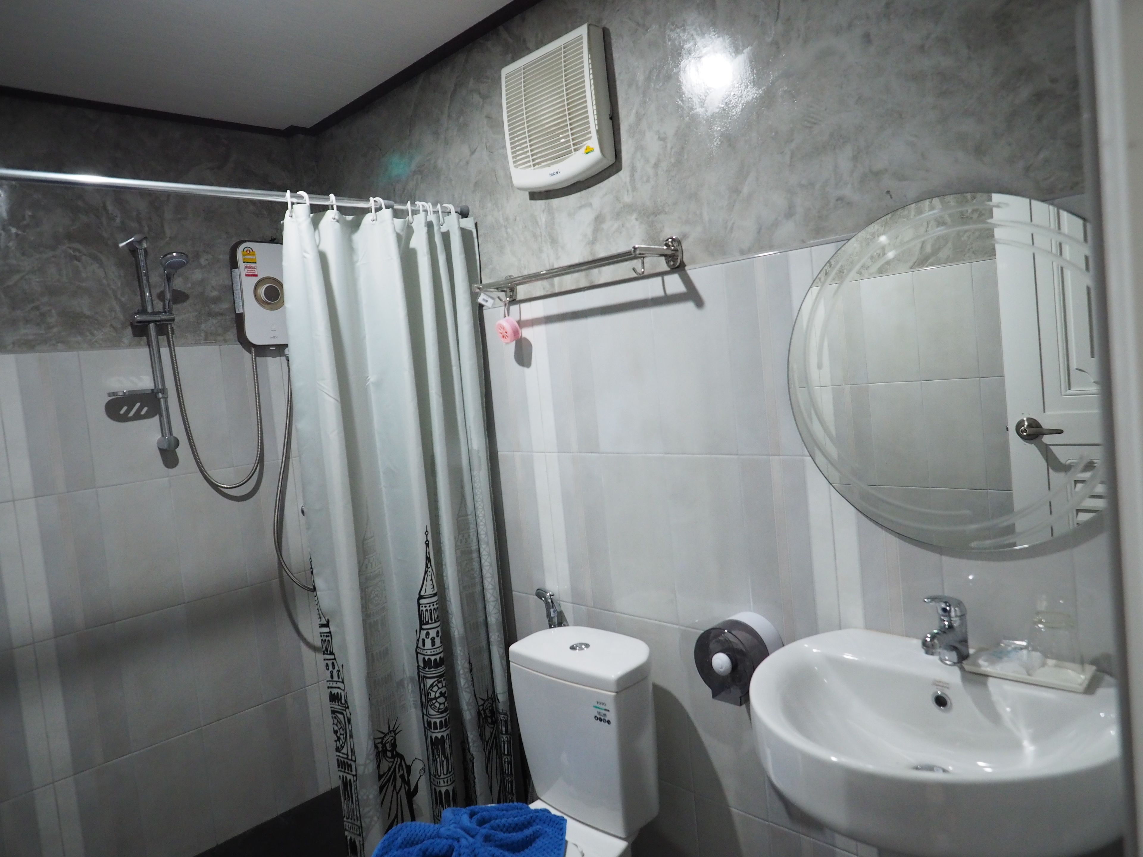 Een badkamer met douche, toilet, wastafel en spiegel.