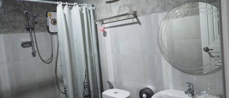 Un baño con ducha, inodoro, lavamanos y espejo.
