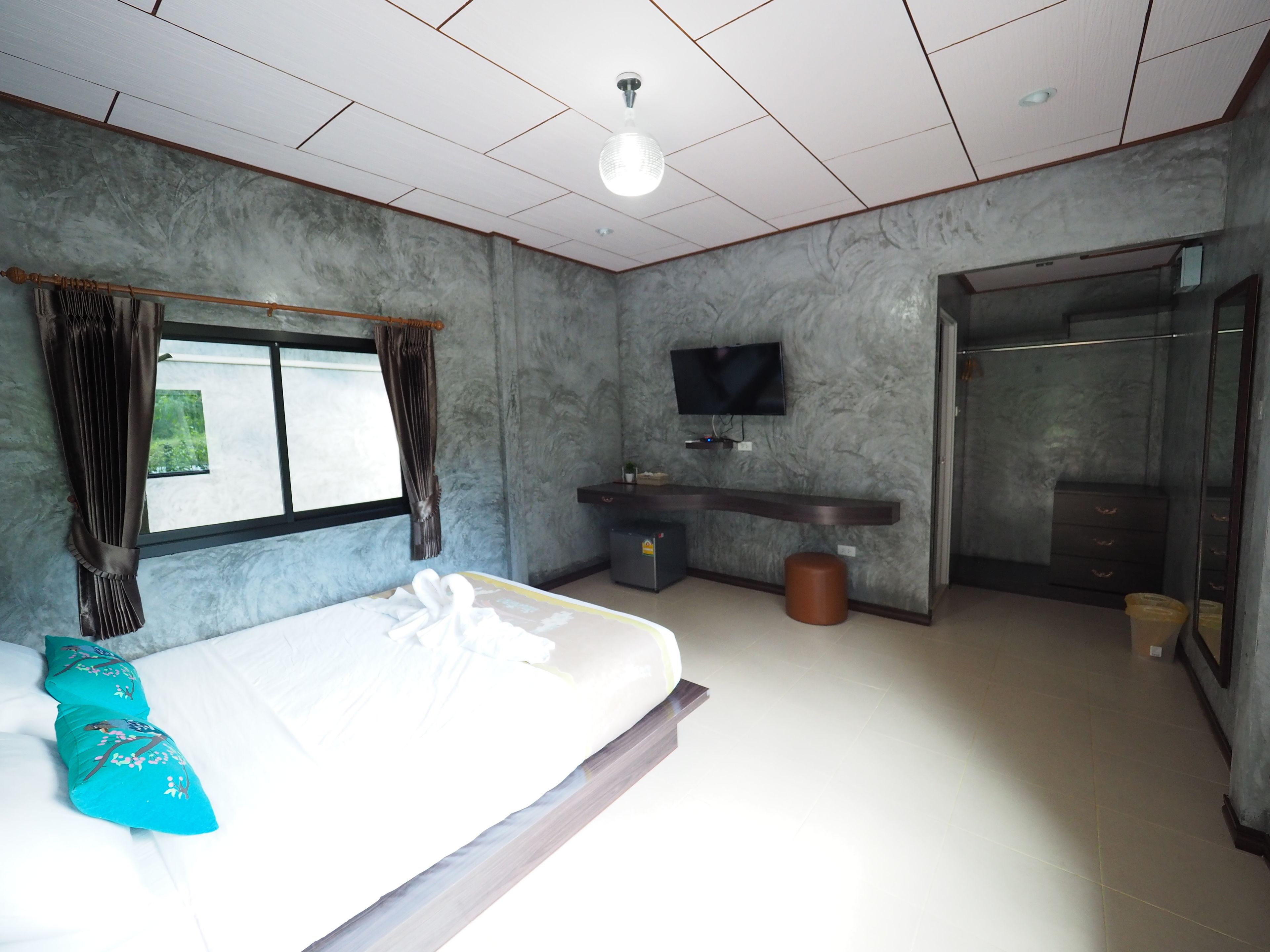 Quarto de hotel moderno com cama, televisão, banheiro e vista para o exterior.