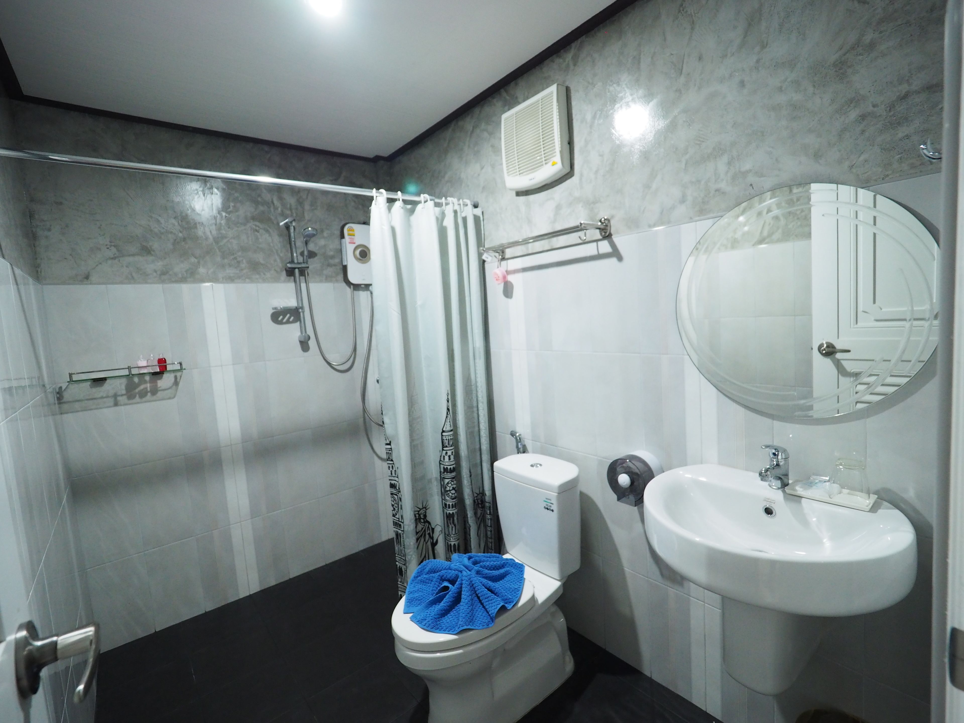 A modern bathroom with a shower, toilet, sink, and a large mirror.