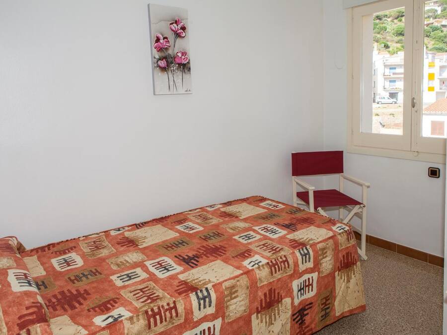 Una habitación pequeña con una cama individual, una silla y una ventana.